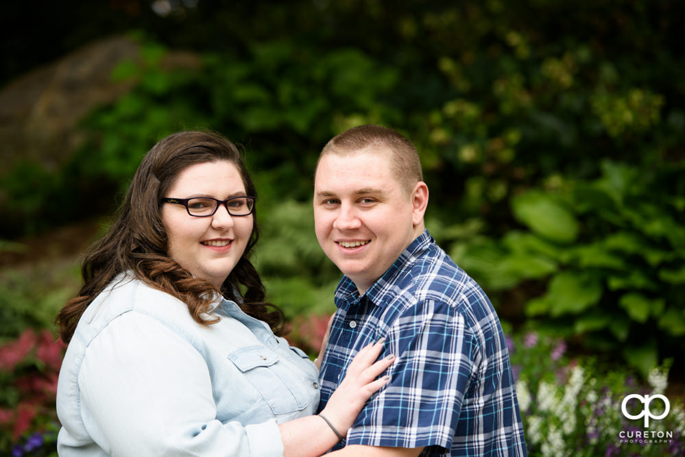 Engaged couple smiling at the camera.