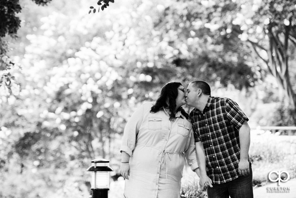 Black and white photo of a couple kissing each other in Falls Park.