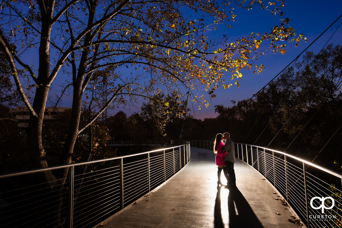 Engaged couple kissing on Liberty Bridge in Falls Park in downtown Greenville,SC.