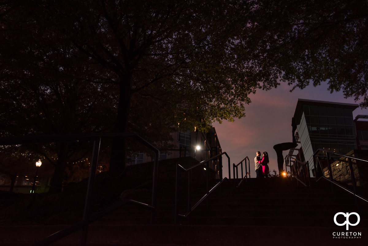 Engaged couple at the top of the steps in Falls Park on the Reedy at sunset.