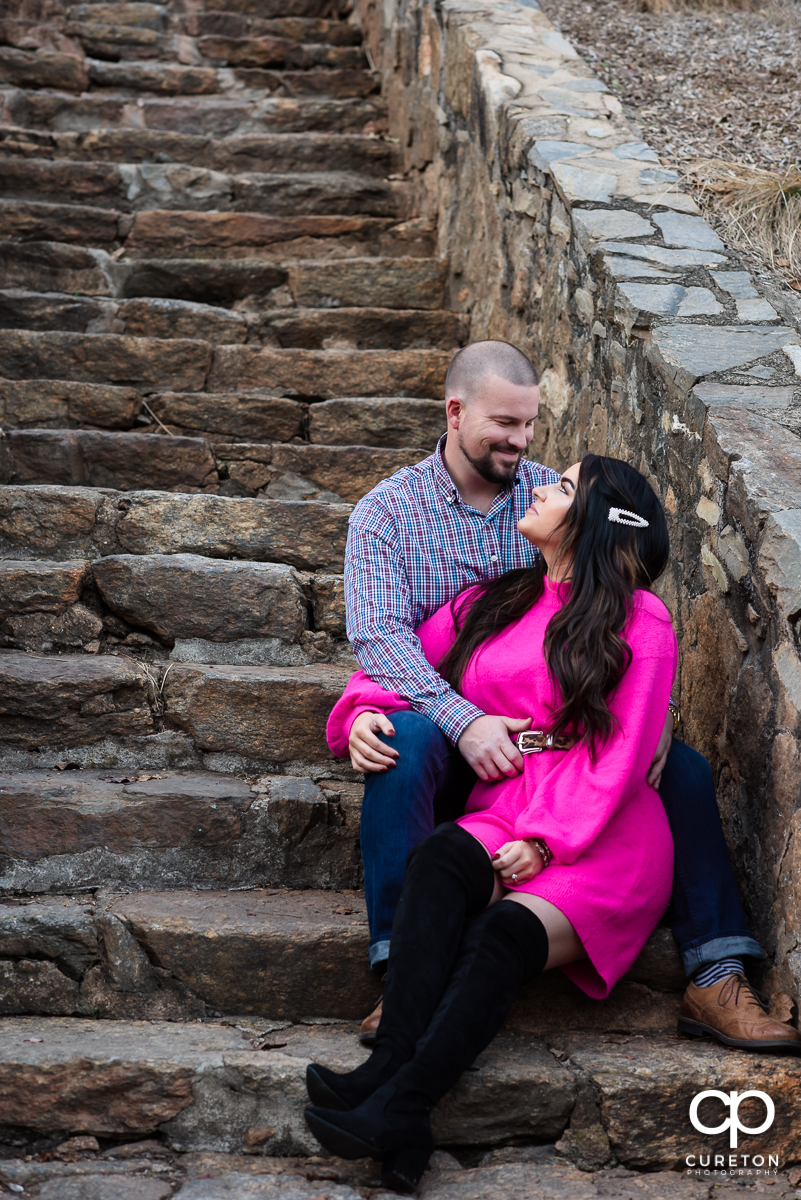 Engaged couple sitting on some steps.
