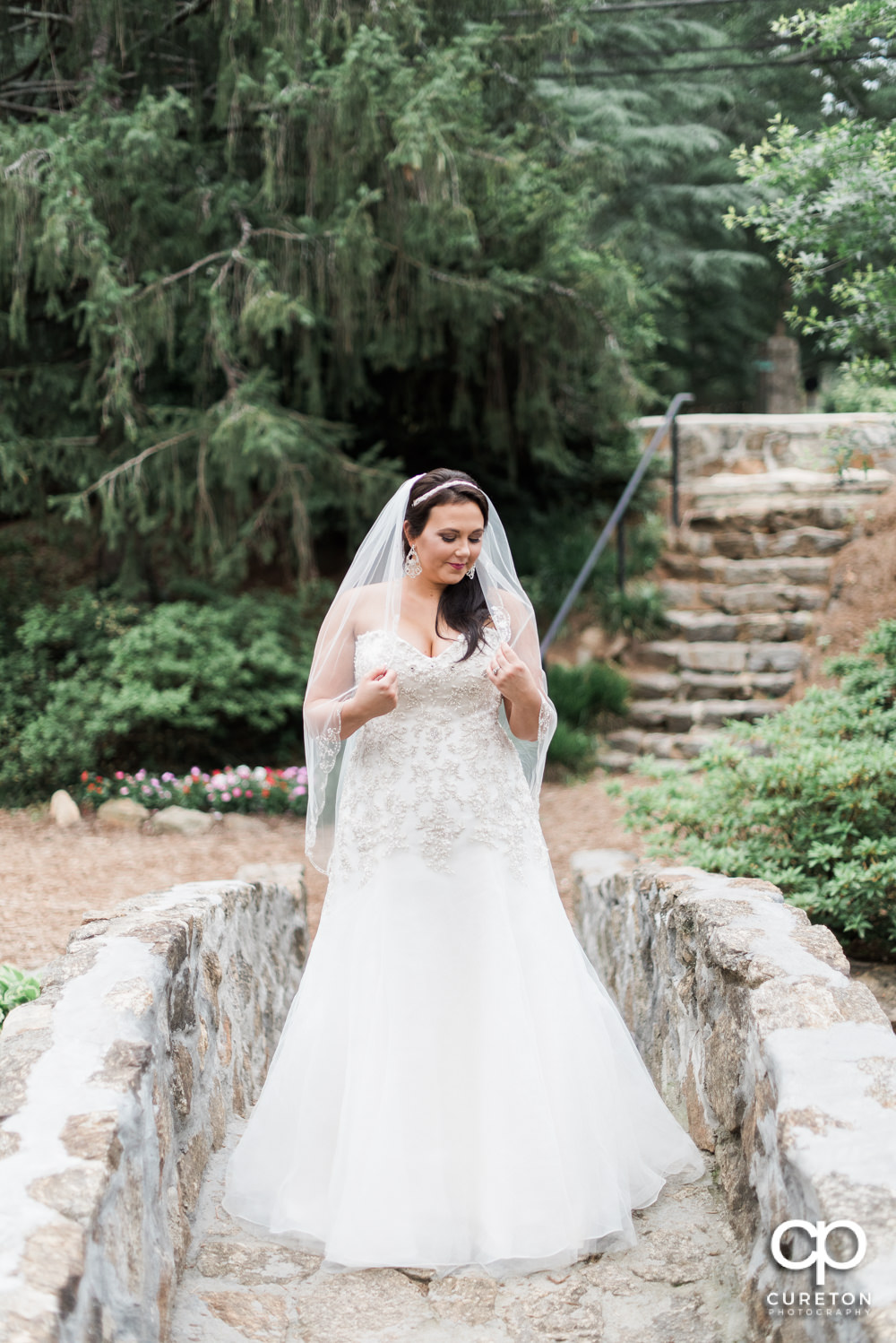 Bride holding her veil on the stone bridge at the rock quarry in Greenville.
