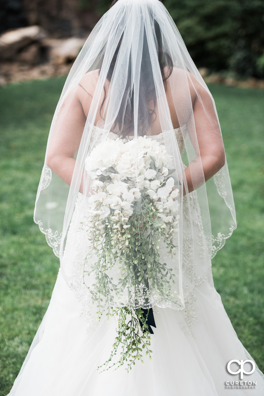 Bride holding her flowers behind her back.