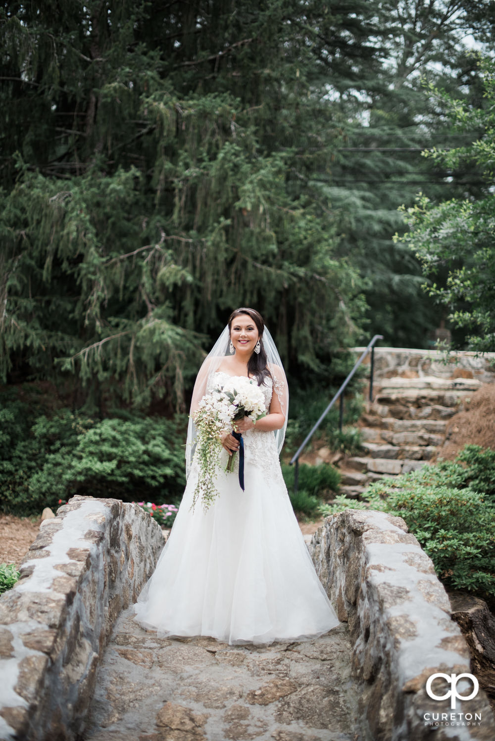 Bride standing on the stone bridge over the Reedy River at the Rock Quarry Garden in downtown Greenville.