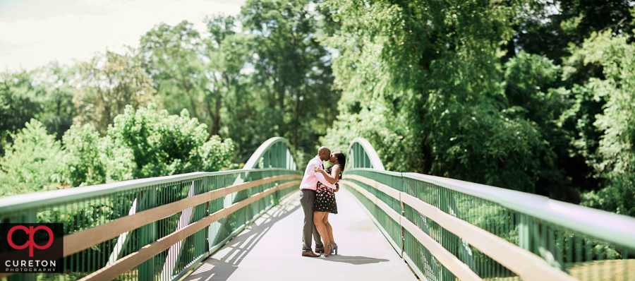 Married couple dancing on a bridge during their anniversary photo session in Greenville,SC at the Rock Quarry Garden..