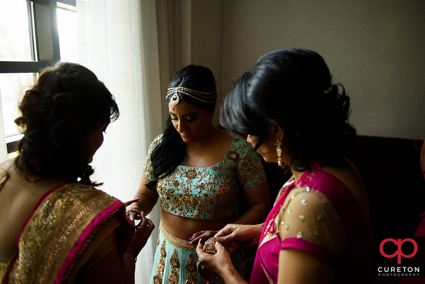 Indian bride putting on her jewelry.