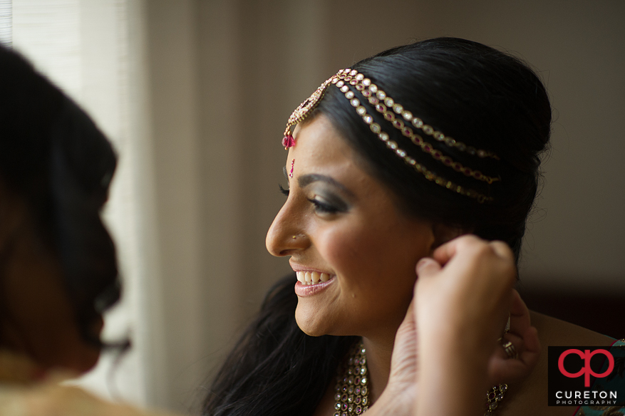Indian bride putting on her earrings.