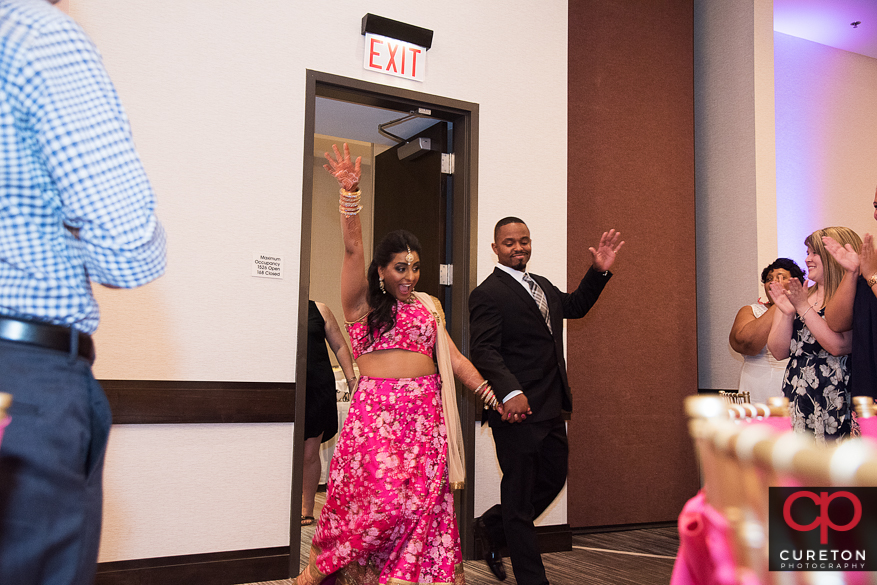 Indian bride and groom making an entrance into the wedding reception.