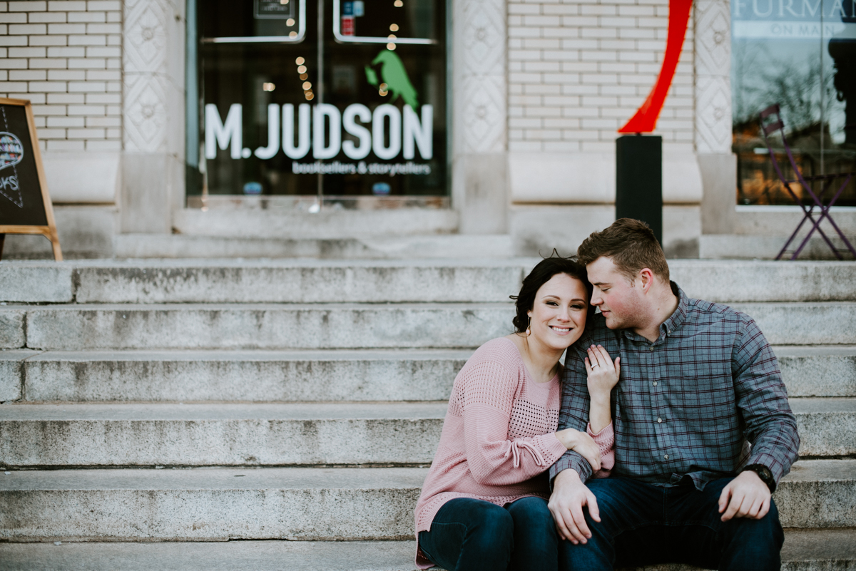 Engaged couple sitting on steps in Greenville,SC.