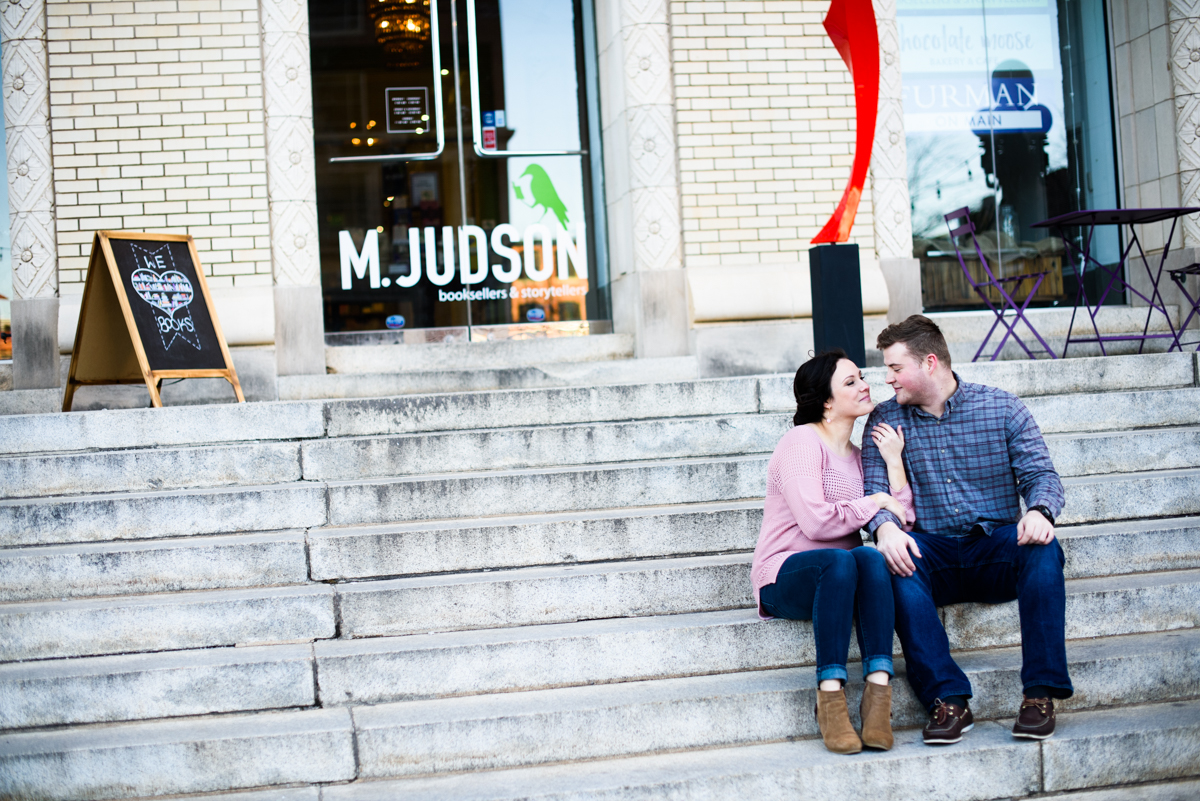 Bride and Groom sitting on the steps in downtown Greenville during their engagement session.