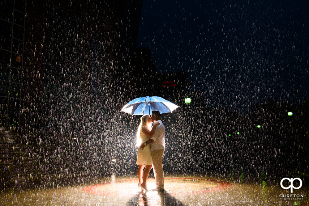 Future bride and groom standing in the rain in the middle of downtown Greenville SC during their engagement session