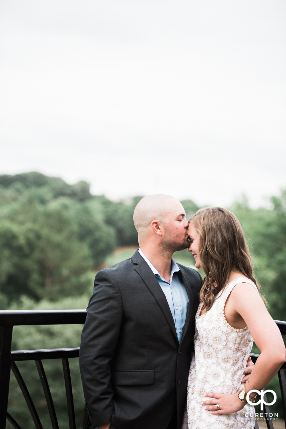 Groom kissing his bride's forehead at their wedding rehearsal dinner at the Thornblade Country Club in Greenville , SC .