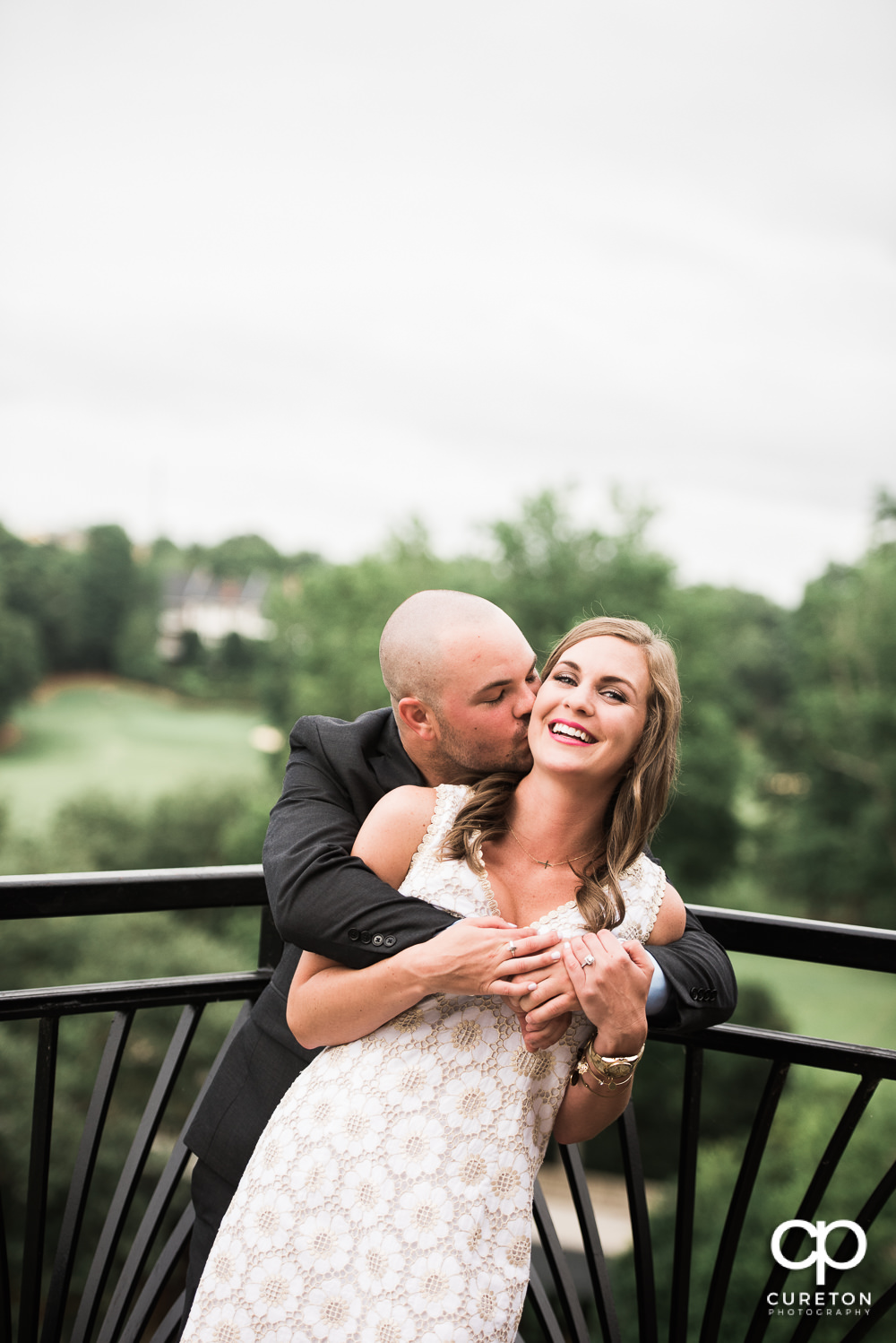 Groom kissing his bride at their wedding rehearsal dinner at the Thornblade Country Club in Greenville , SC .