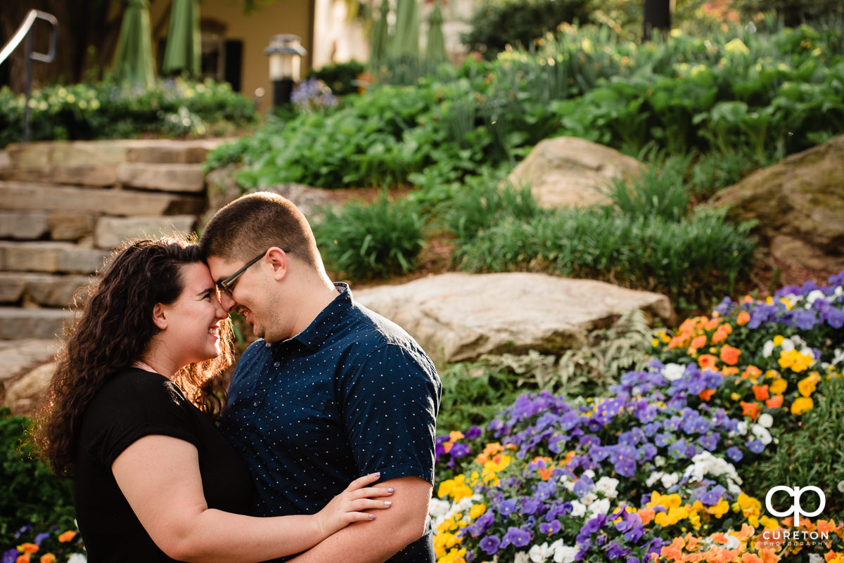 Engaged couple hugging in front of flowers in downtown Greenville,SC.