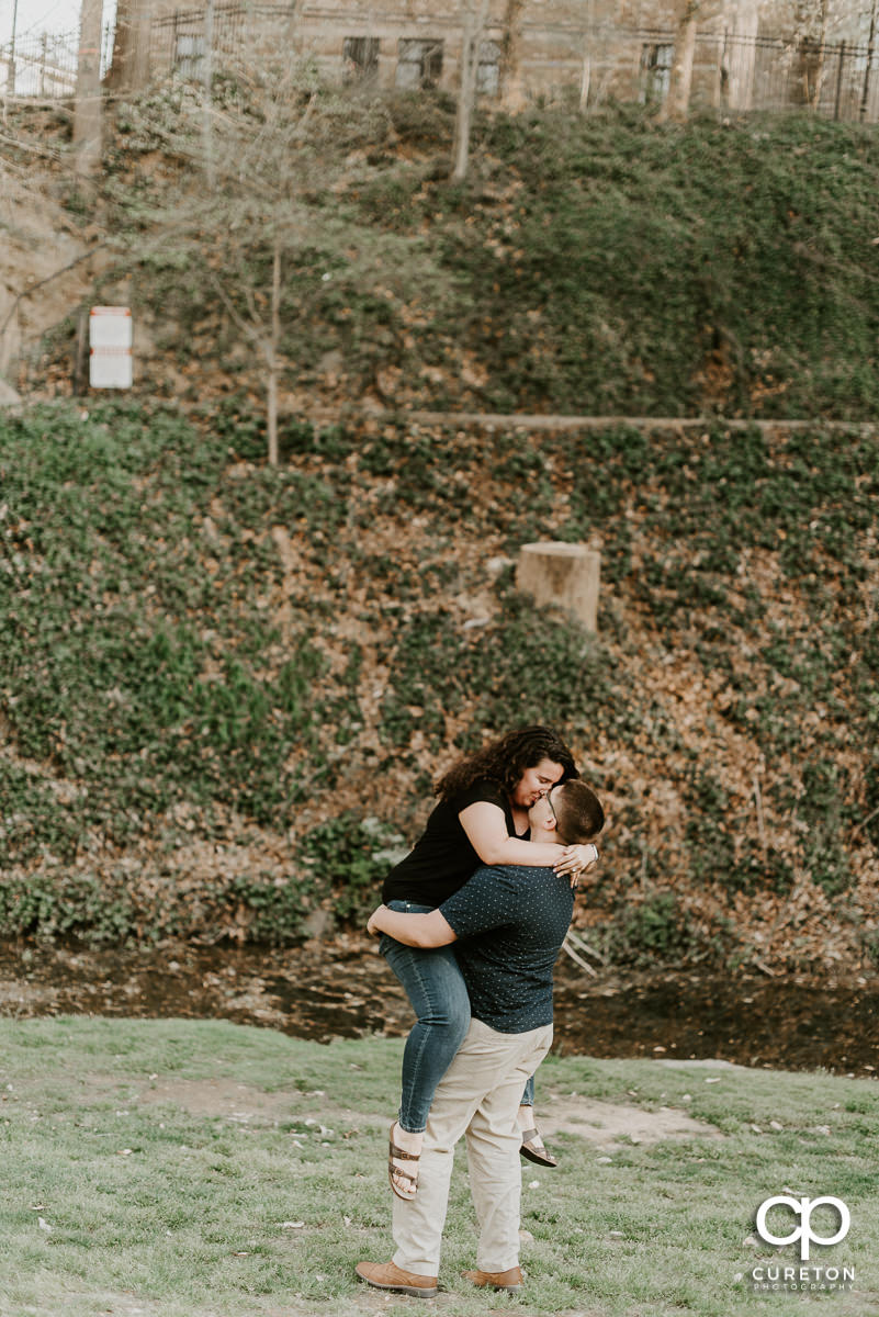 Man lifting his fiancee in the air.