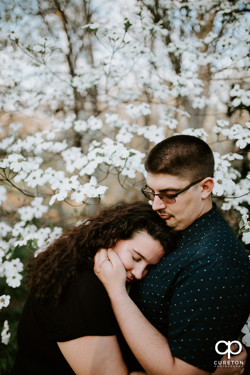 Engaged couple standing in flowers.