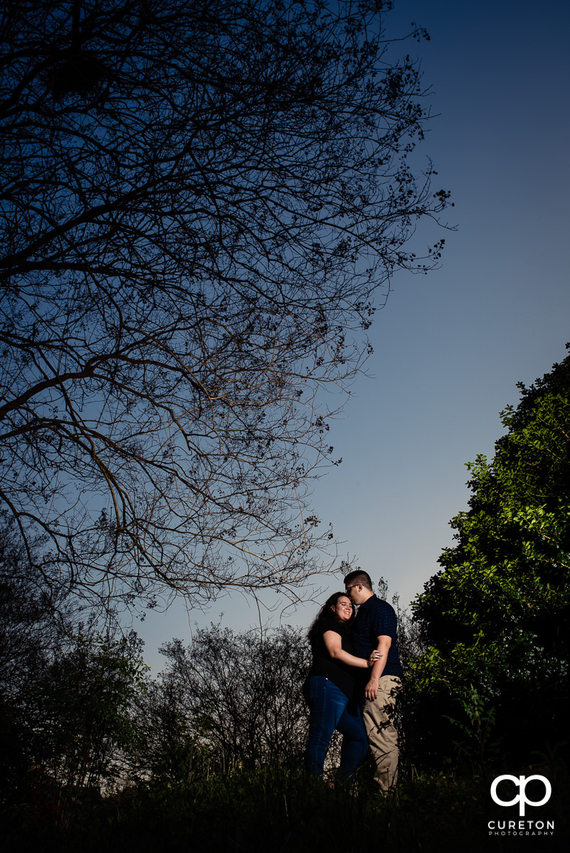 Engaged couple standing in the bushes.