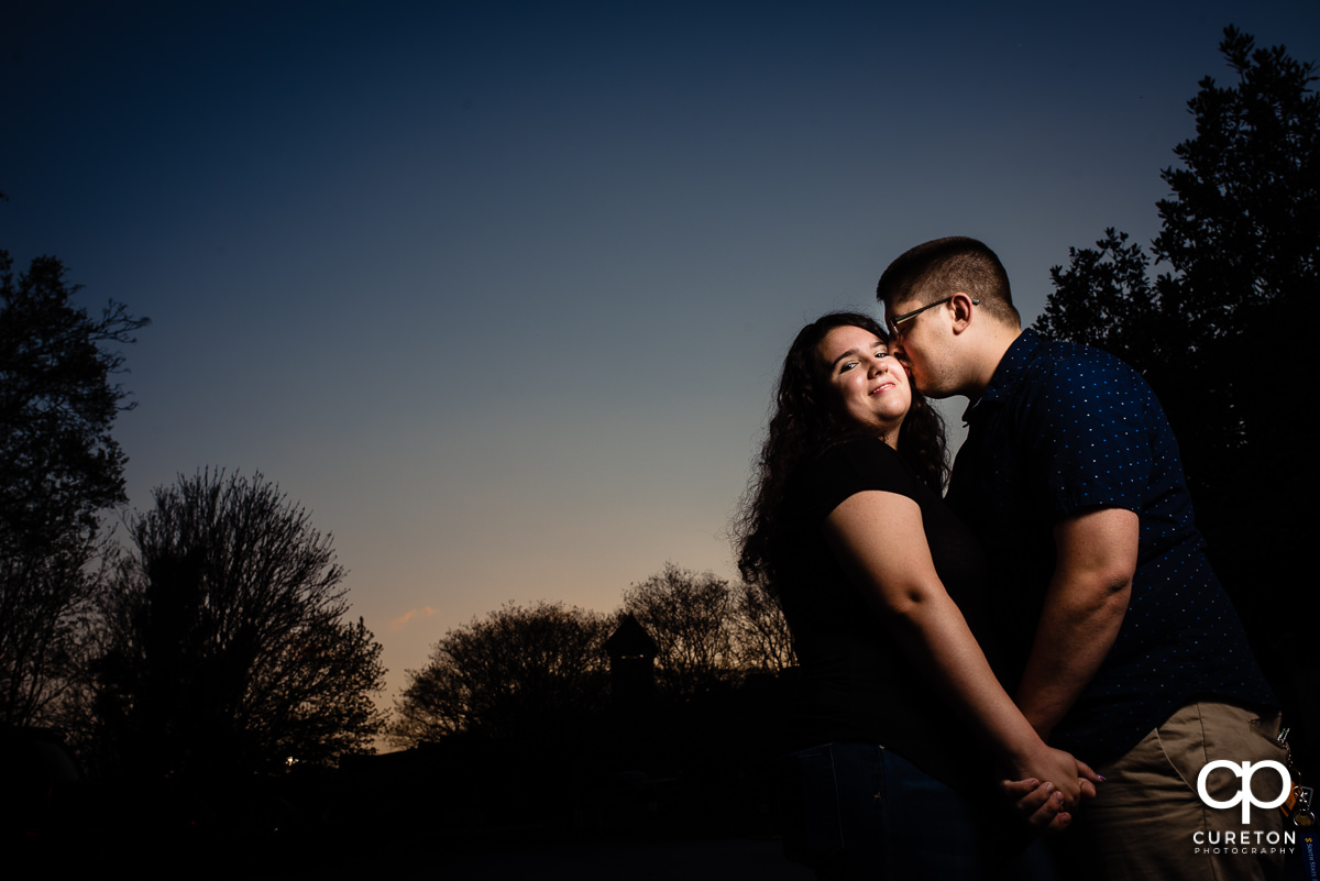 Engaged couple kissing at sunset.