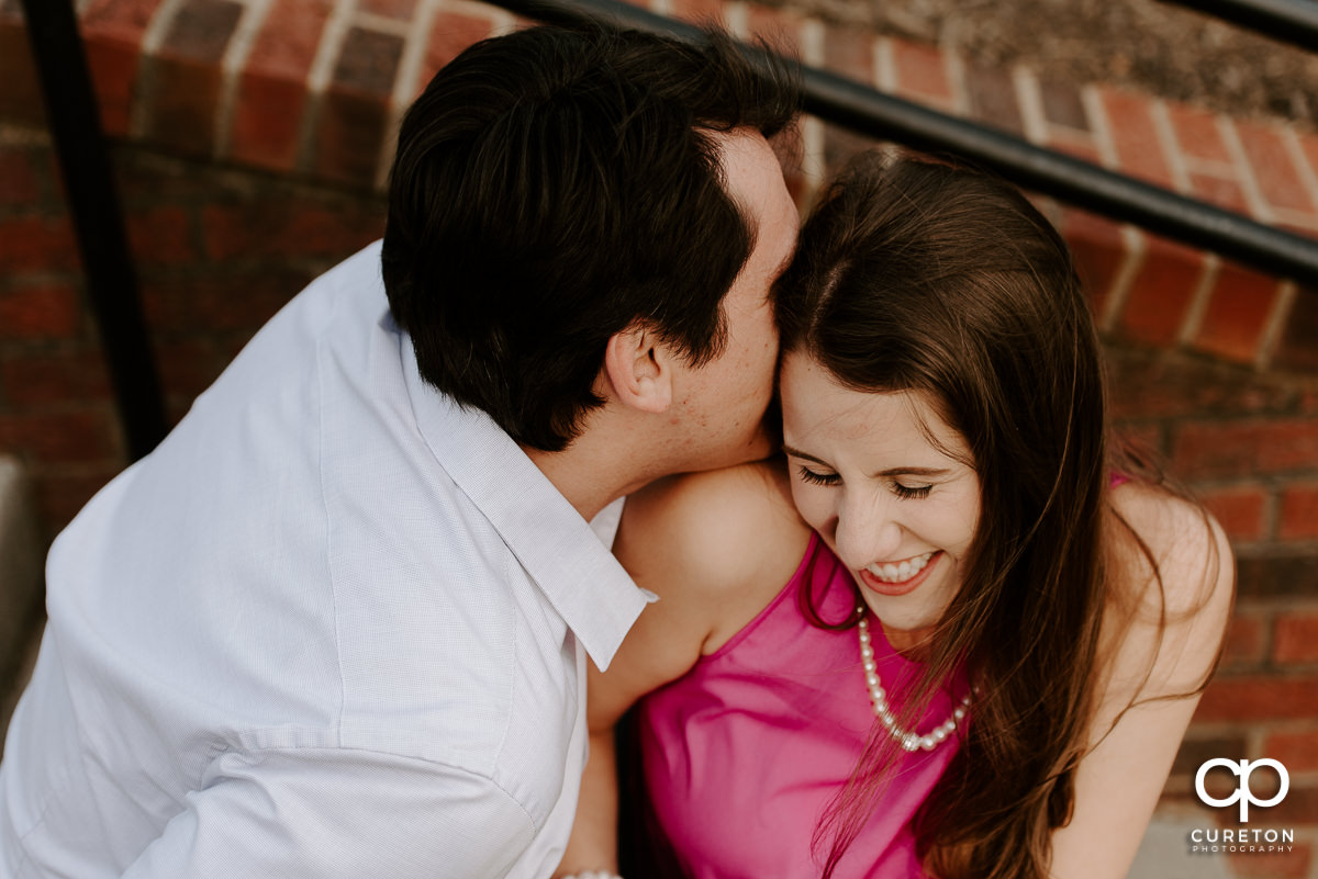 Man whispering into his fiancee's ear during their engagement session.