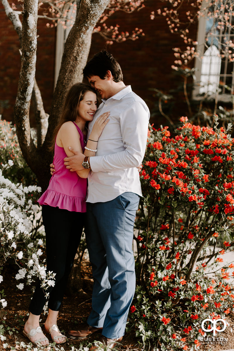 Engaged couple standing in some flowers.