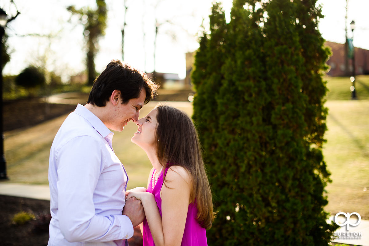 Engaged couple smiling at each other in Greer City Park.