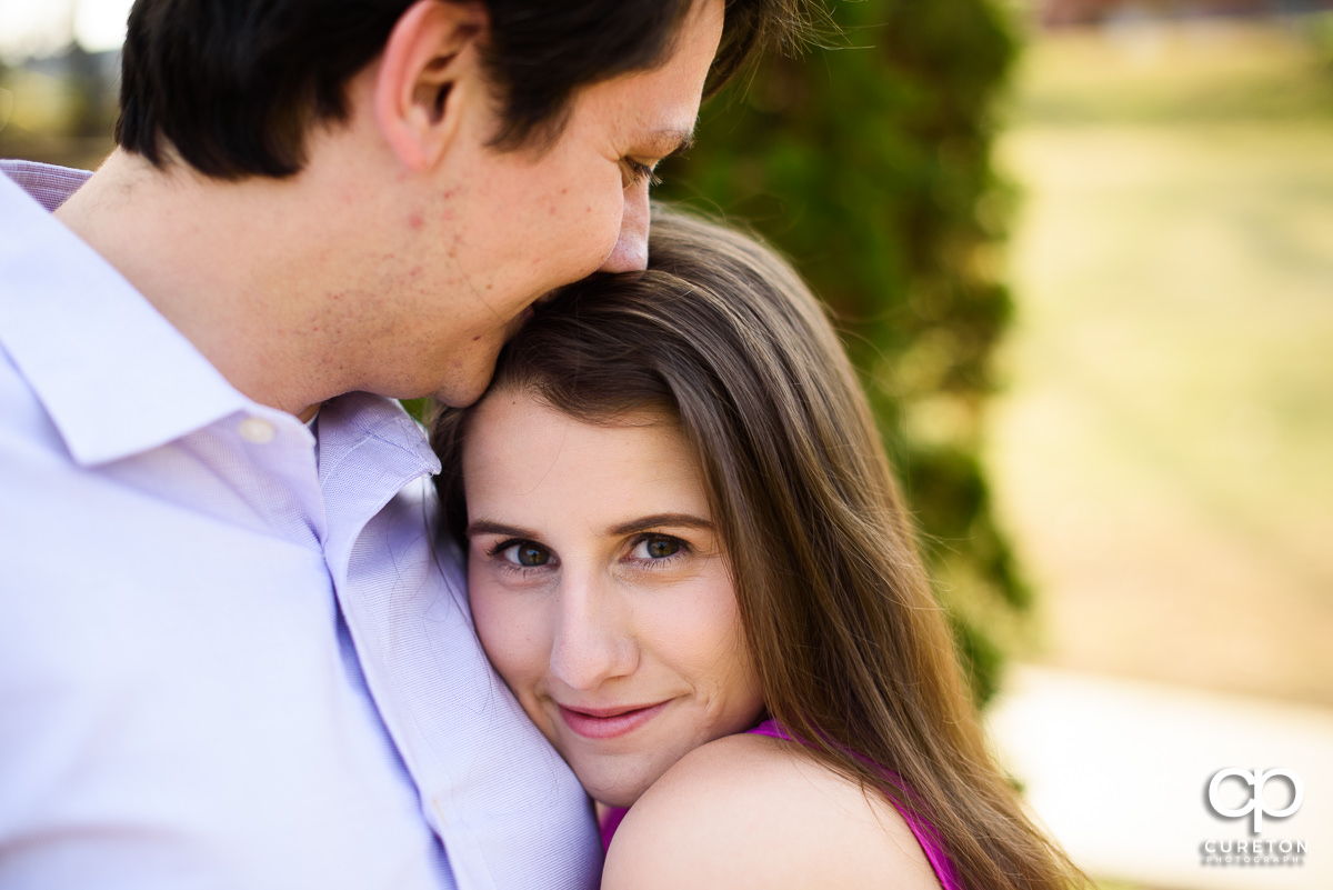 Man kissing his fiancee on the forehead.