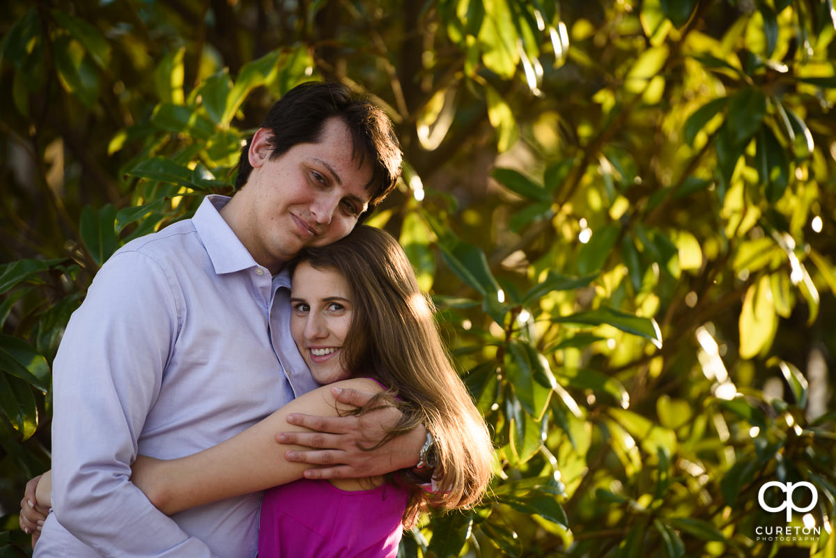 Engaged couple in front of greenery.