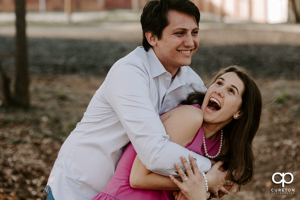 Engaged couple tickling each other in downtown Greer SC.