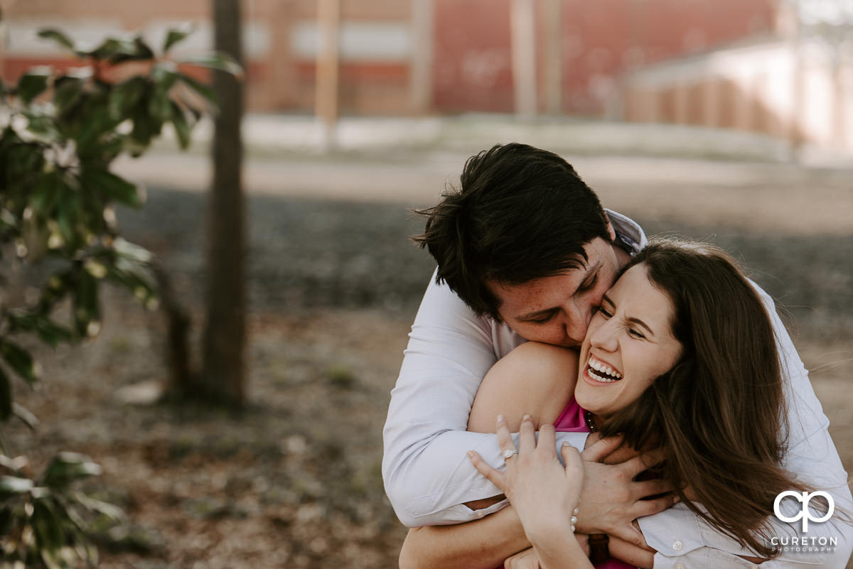 Man kissing his fiancée on the cheek.