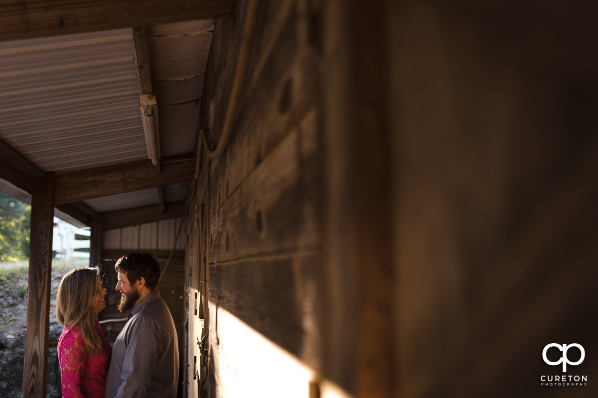 Bride and groom standing outside of a horse stable during a summer engagement session in Greer,SC.