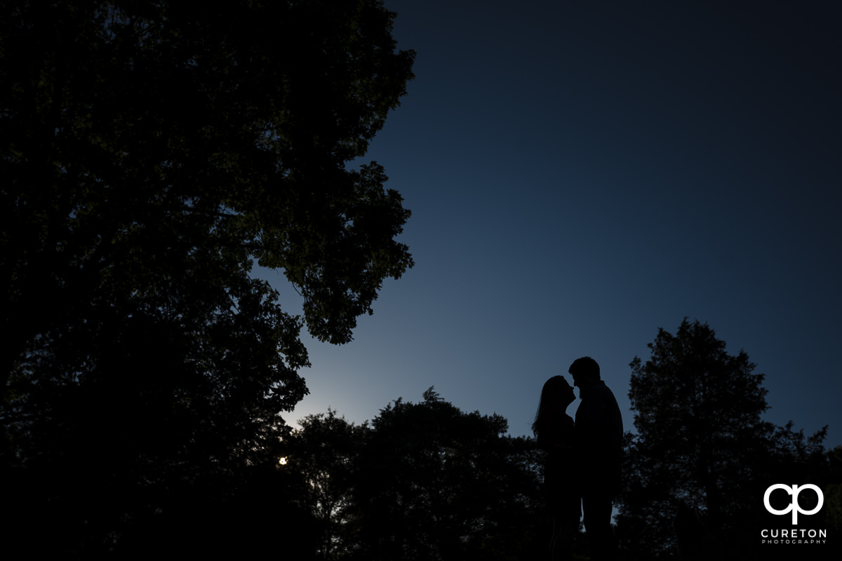 Silhouette of an engaged couple behind a blue sky during a summer engagement session in Greer,SC.