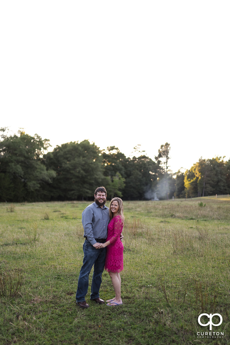 Woman standing in a field with her future husband during a summer engagement session in Greer,SC.