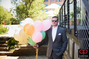 Groom awaits first look with balloons in his hand.