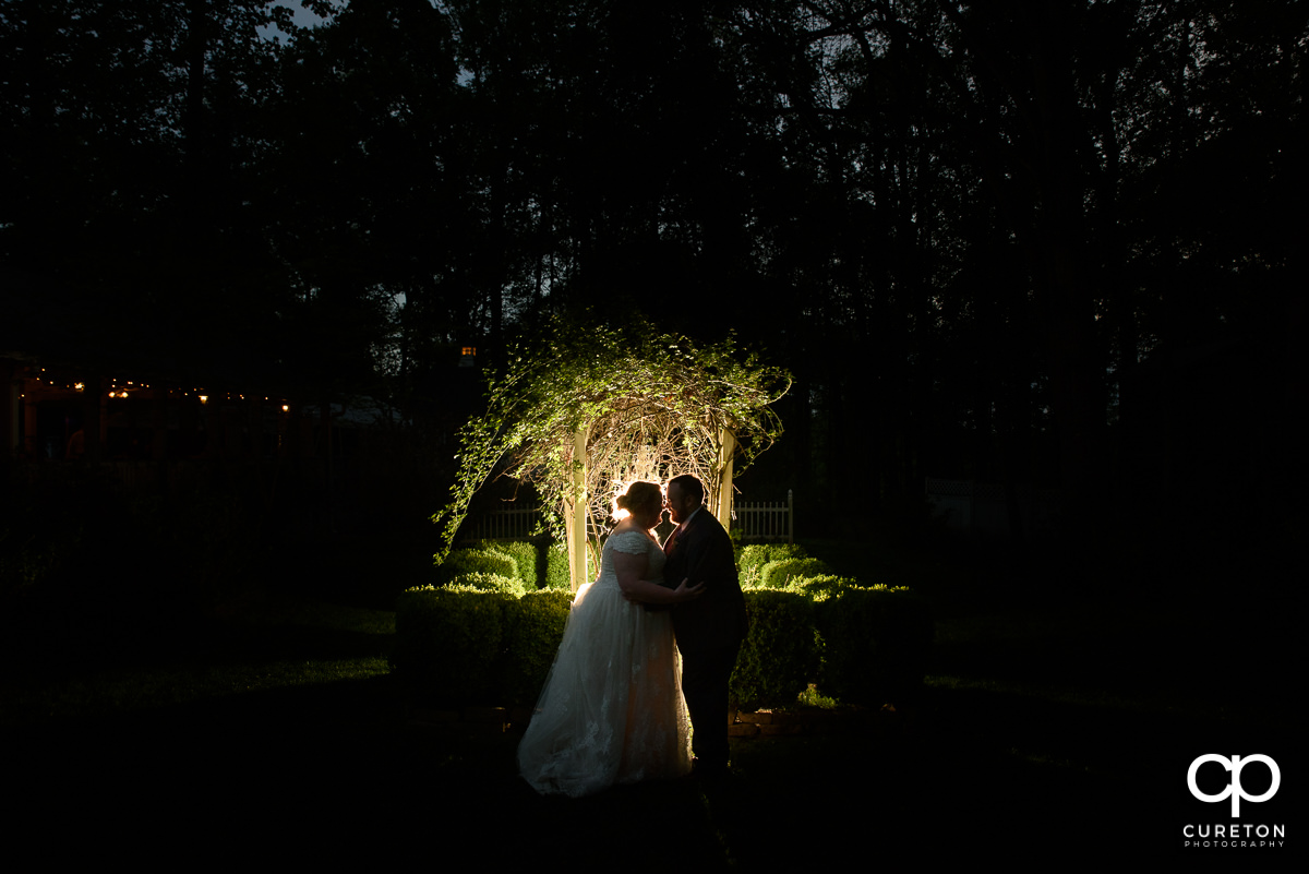 Bride and groom in front of an archway at night at their Grove at Pennington wedding in Greer,SC.