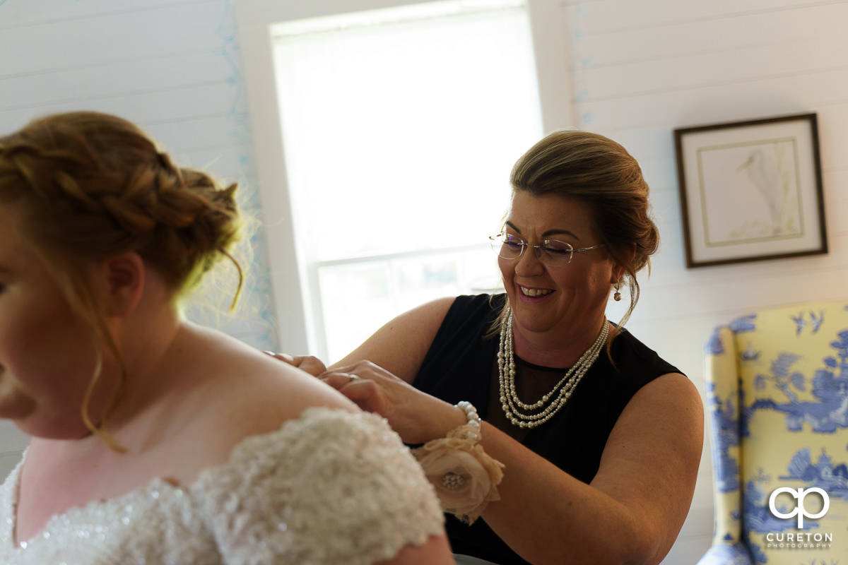 Bride's mother helping her into her dress.