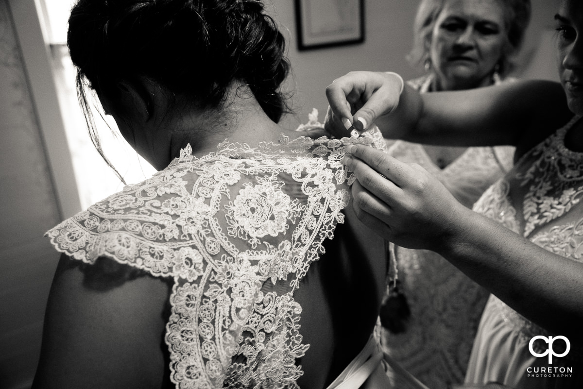 Bride's sisters helping her into her dress.