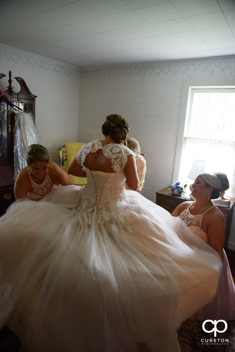 Bridesmaids helping fluff the bride's dress.