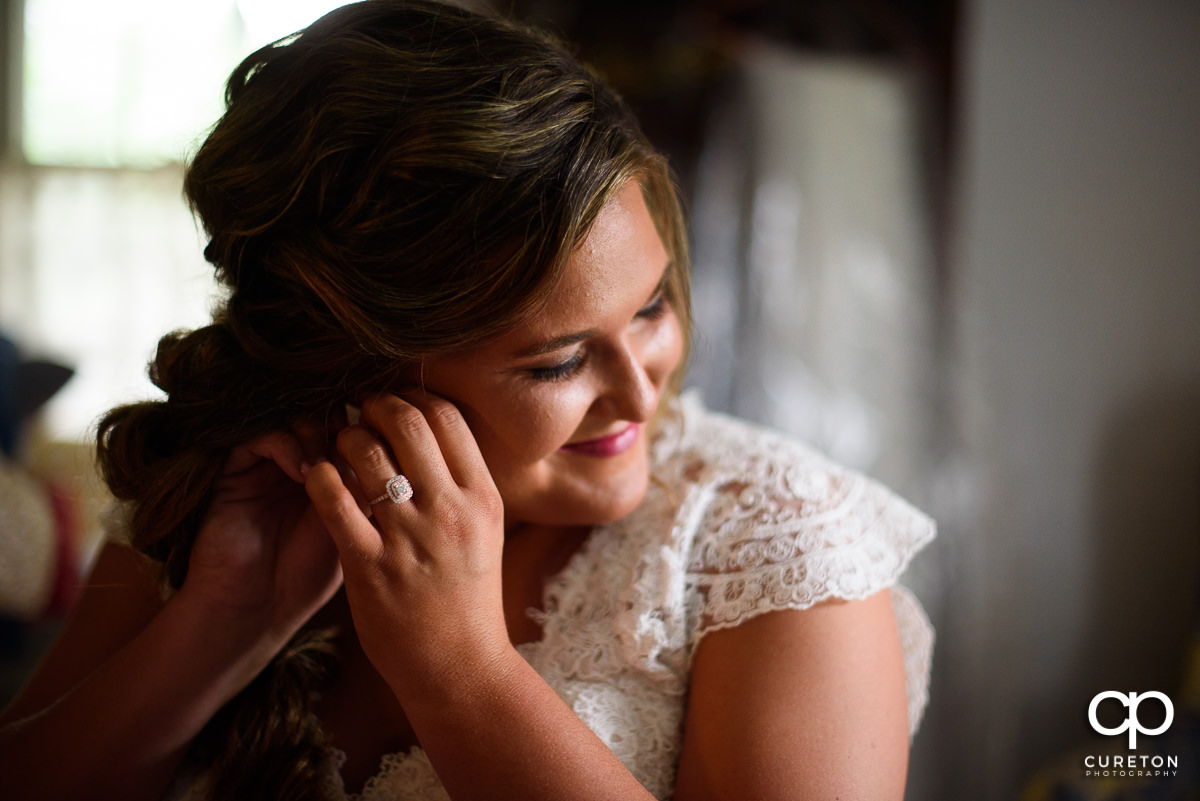 Bride putting on her earrings.