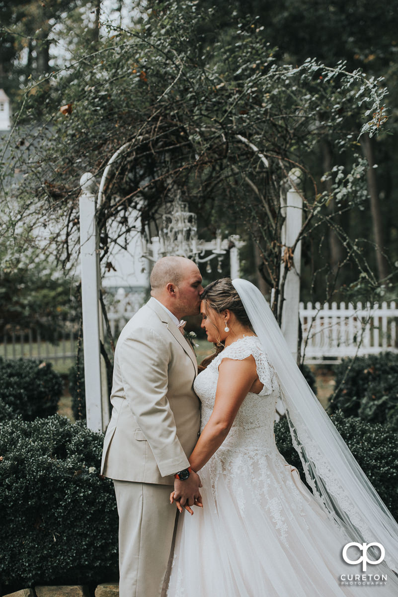 Groom kissing his bride on the forehead before the Grove at Pennington wedding.