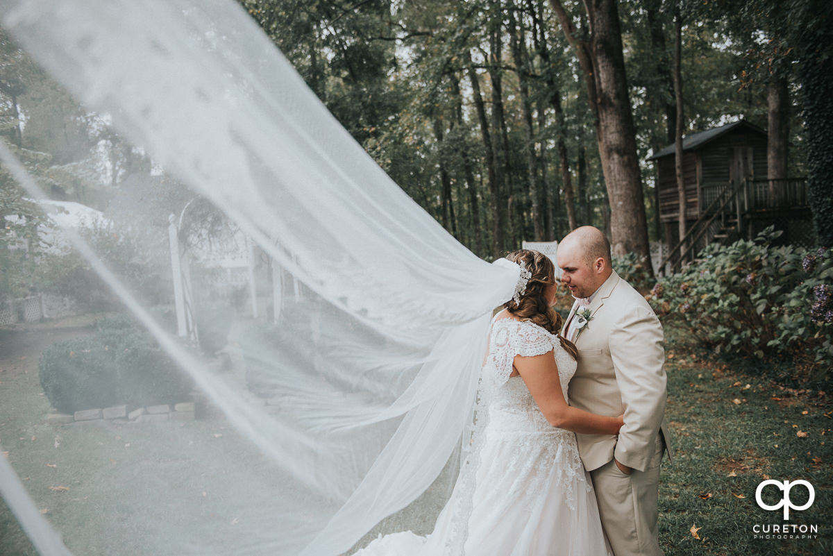 Bride and groom dancing with her cathedral veil blowing in the wind.