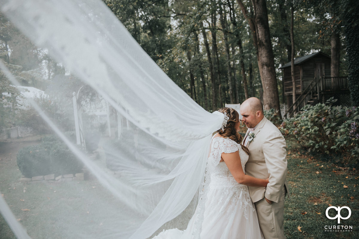 Bride and groom dancing with her cathedral veil blowing in the wind.