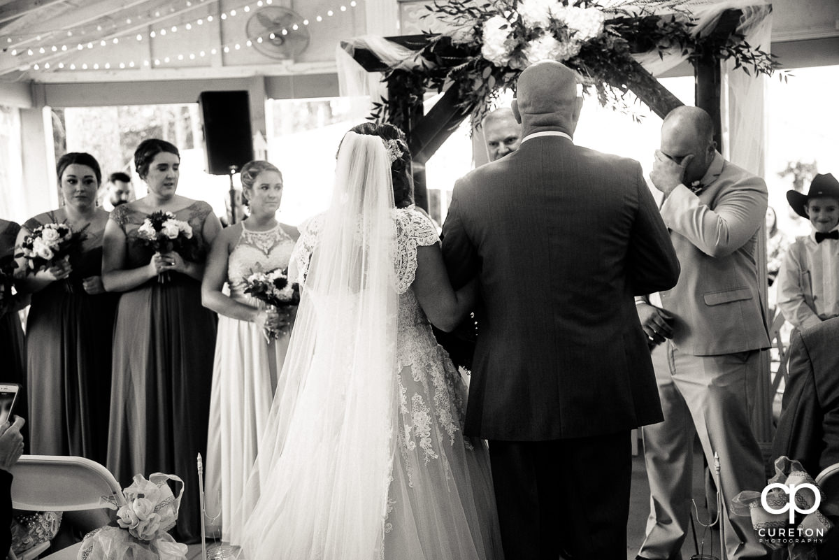 Groom tearing up as a bride walks down the aisle.