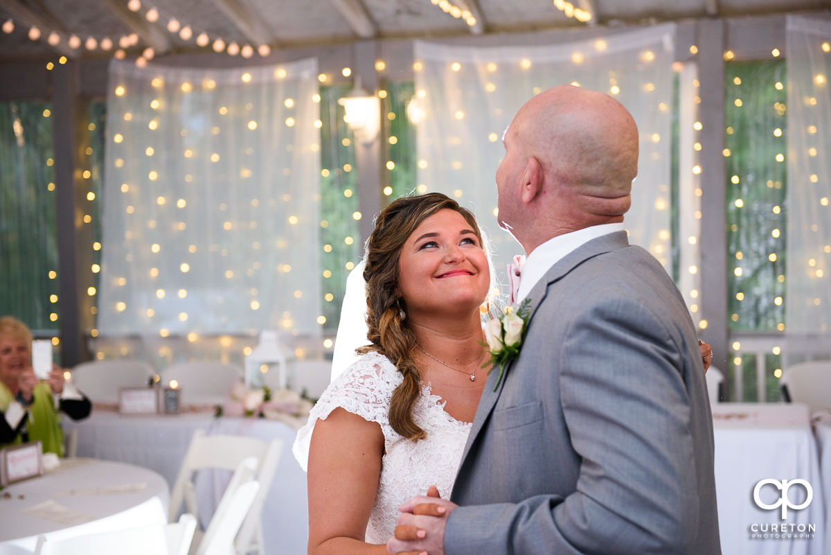 Bride smiling at her father during their first dance.
