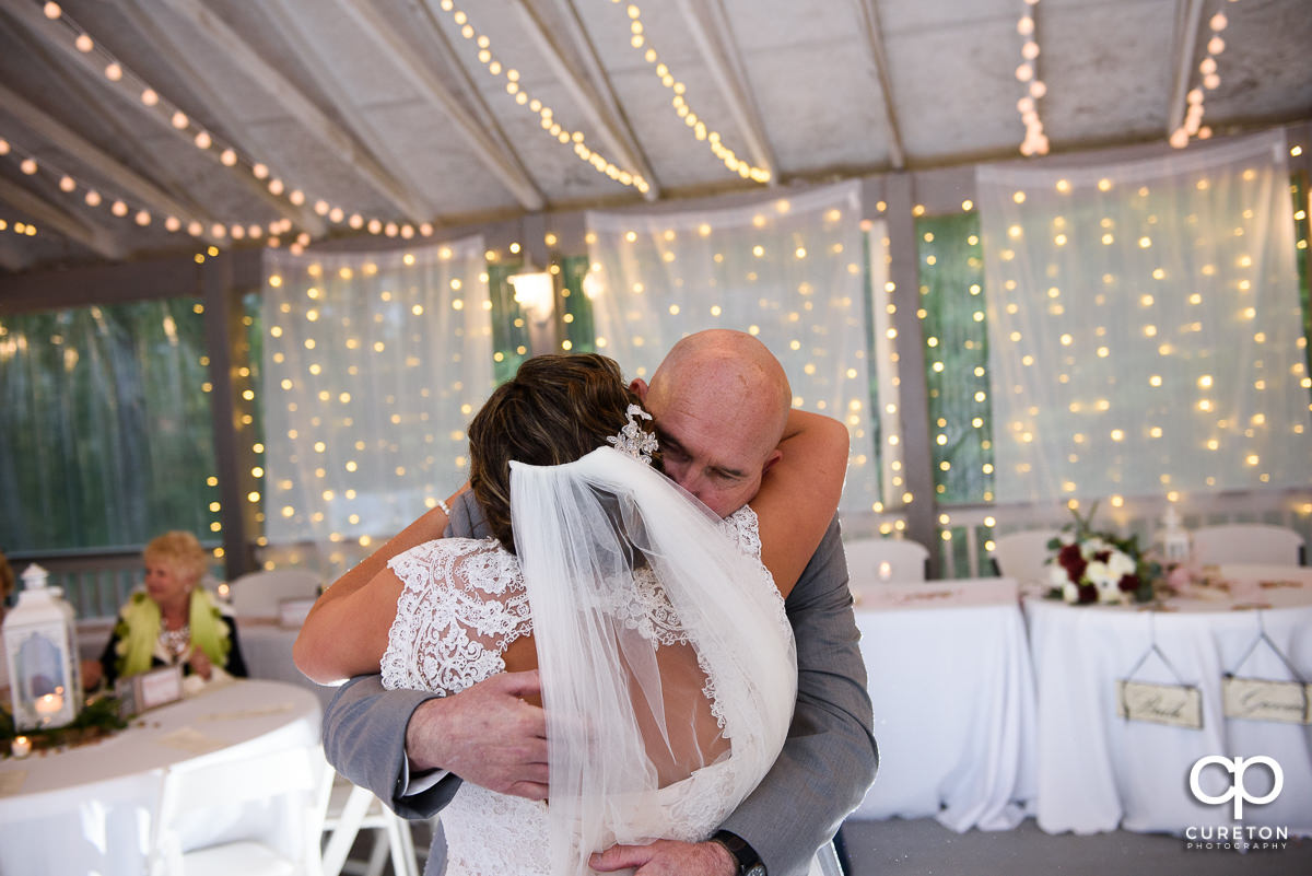 Father of the bride hugging his daughter after they danced at the wedding reception.