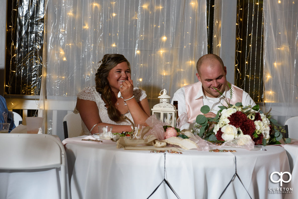 Bride and groom laughing at the toasts.