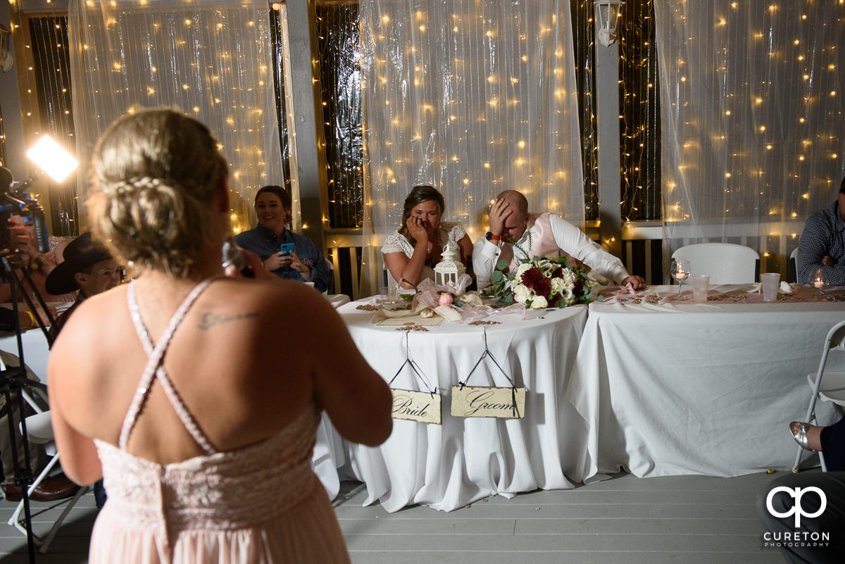 Bride and groom watch as the bride's sister sings a song for them.