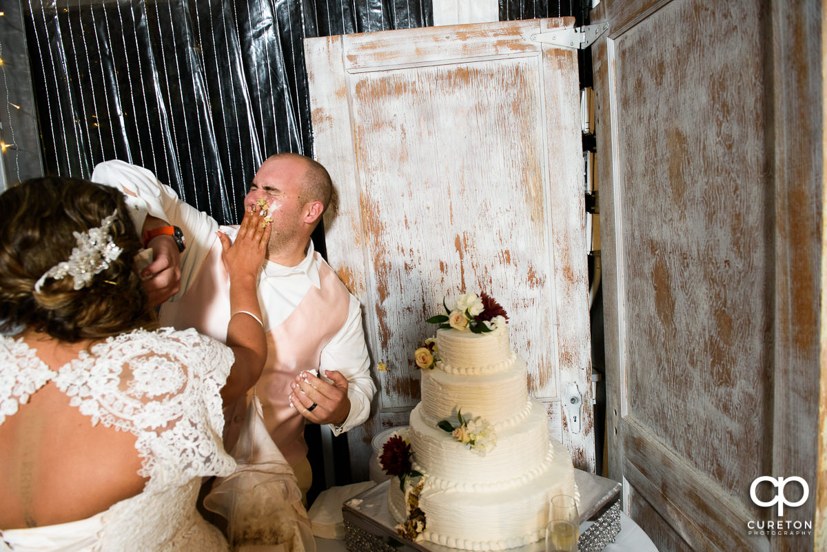 Bride smearing cake on the groom's face.
