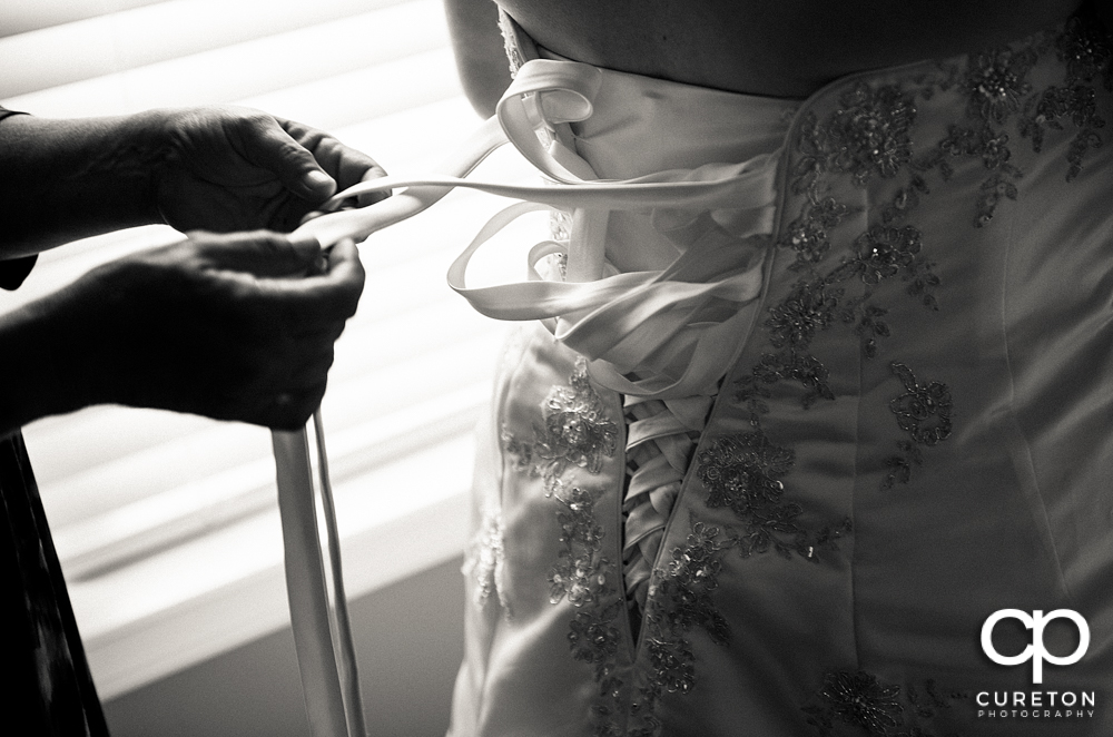 The brides mother helping her with the dress.