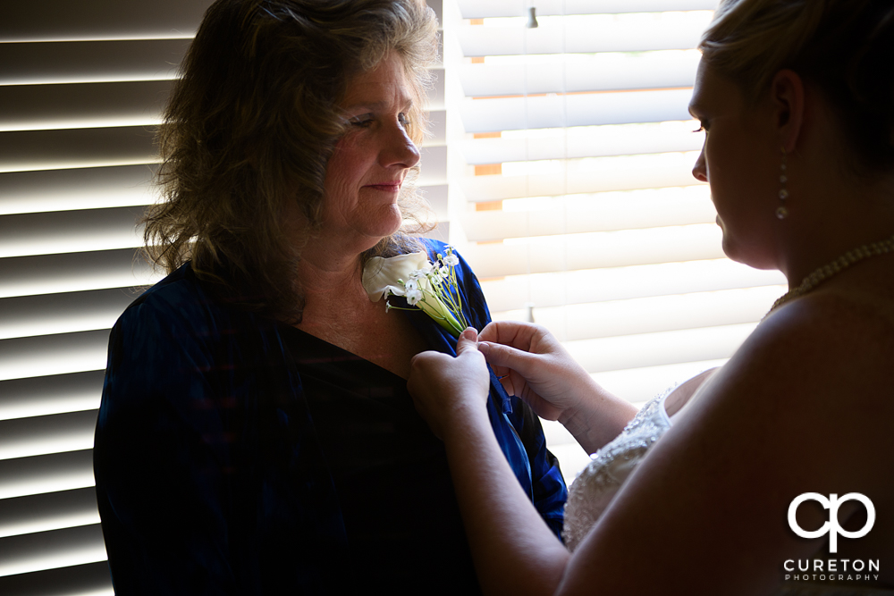 The bride pinning a flower on her mother.