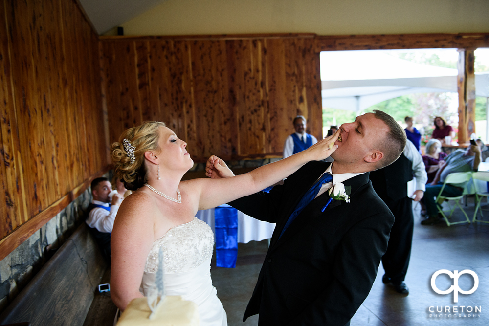 Bride and groom smashing cake.